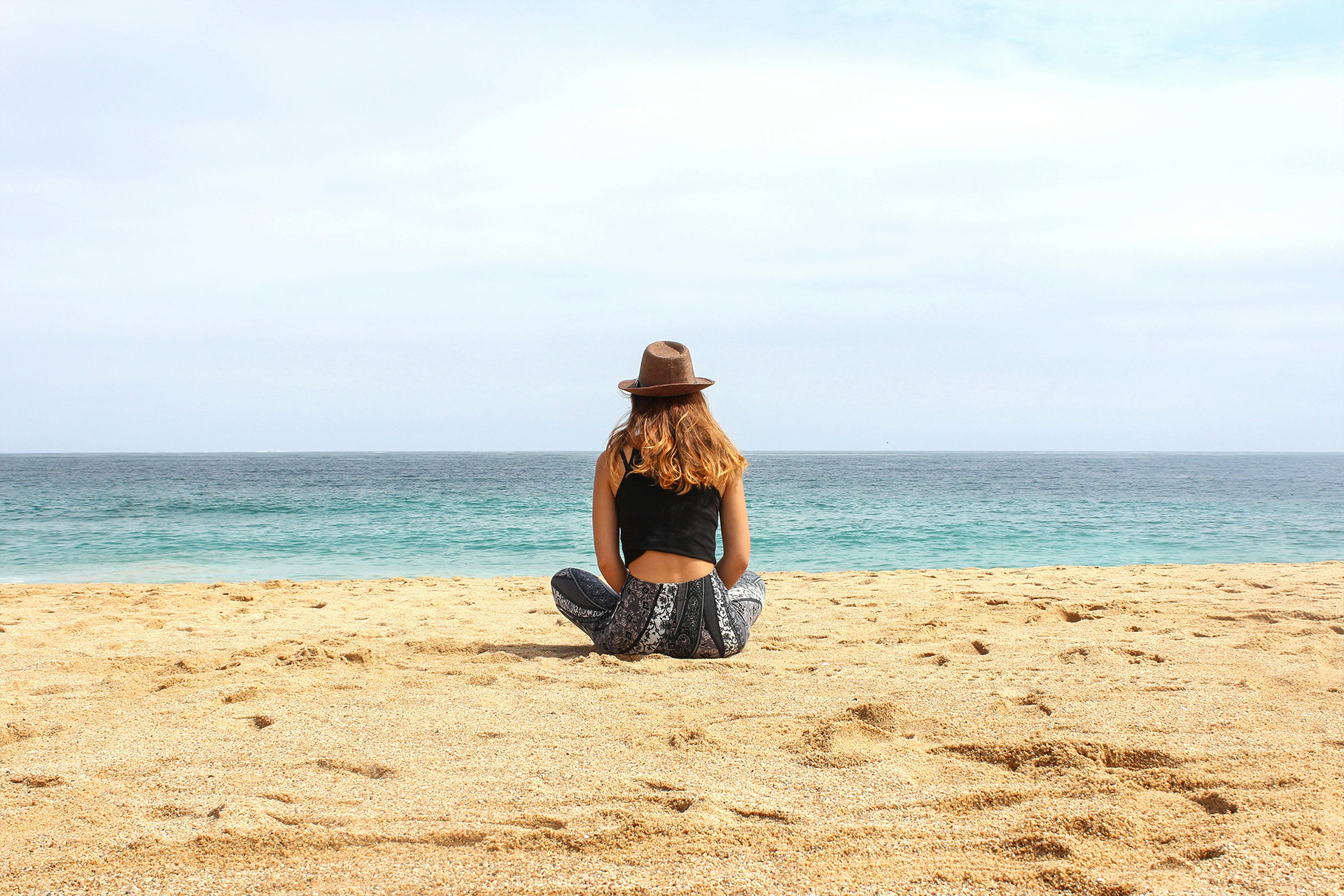 Chica meditando en la playa, pequeños esfuerzos conducen al éxito